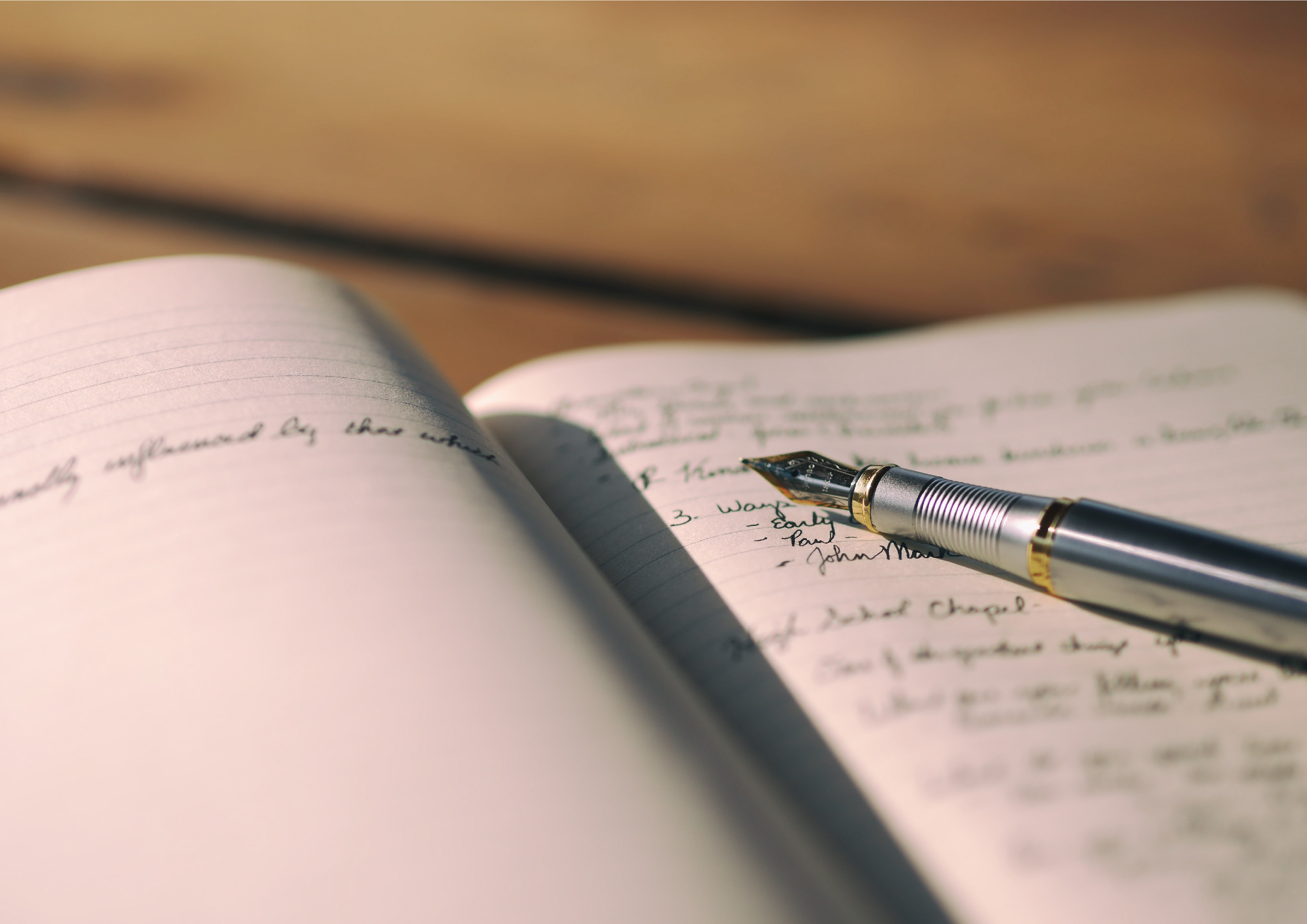 A photo of a pen lying flat on top of an open page of a handwritten book.